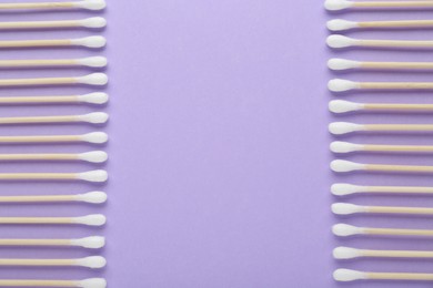 Many wooden cotton buds on violet background, flat lay. Space for text