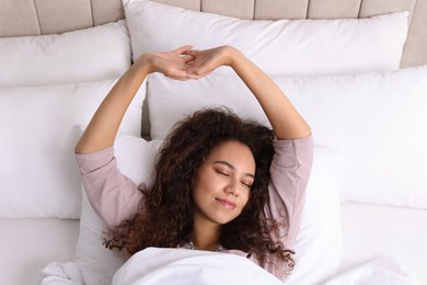 Happy African American woman awakening in bed, top view