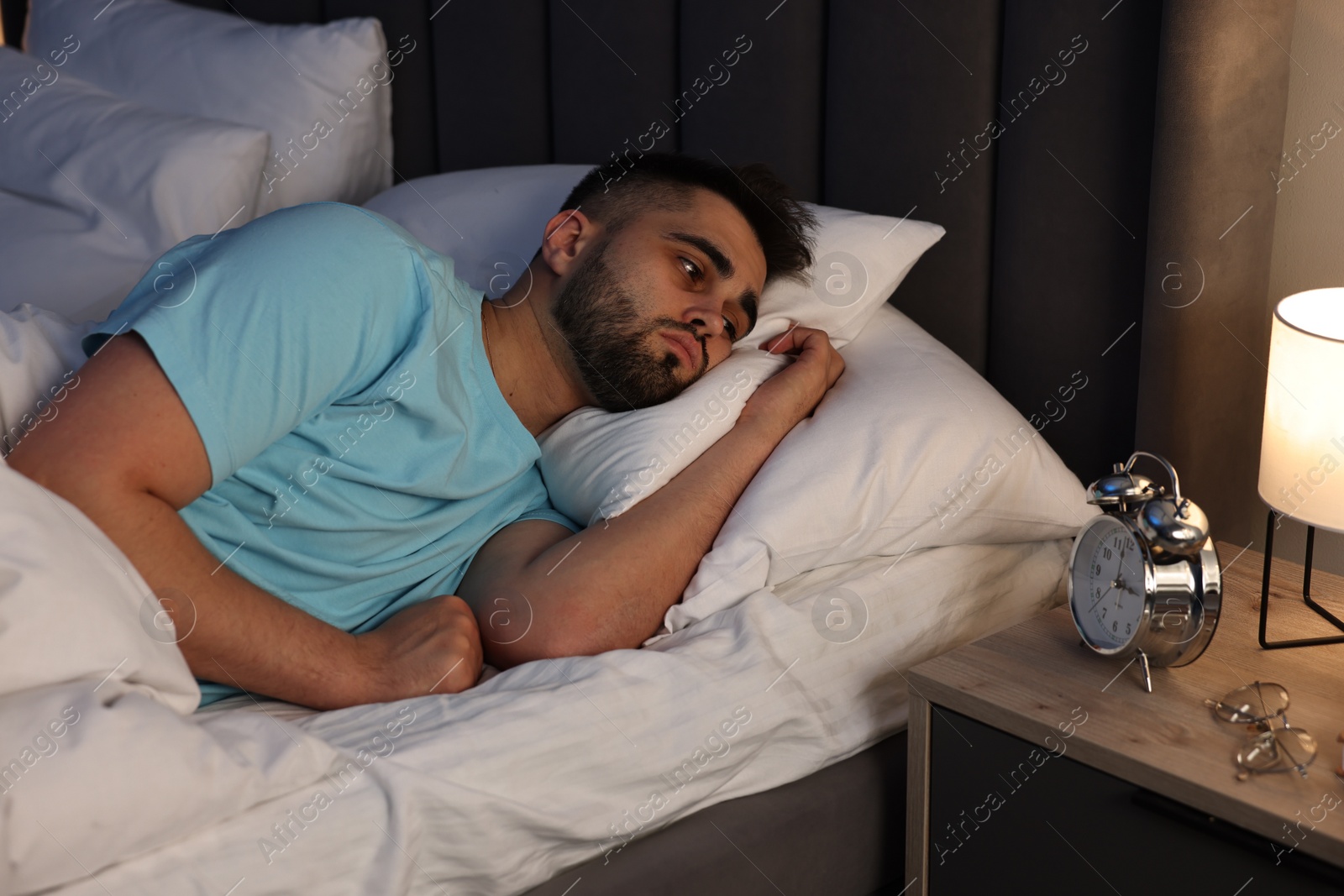 Photo of Frustrated man suffering from insomnia in bed