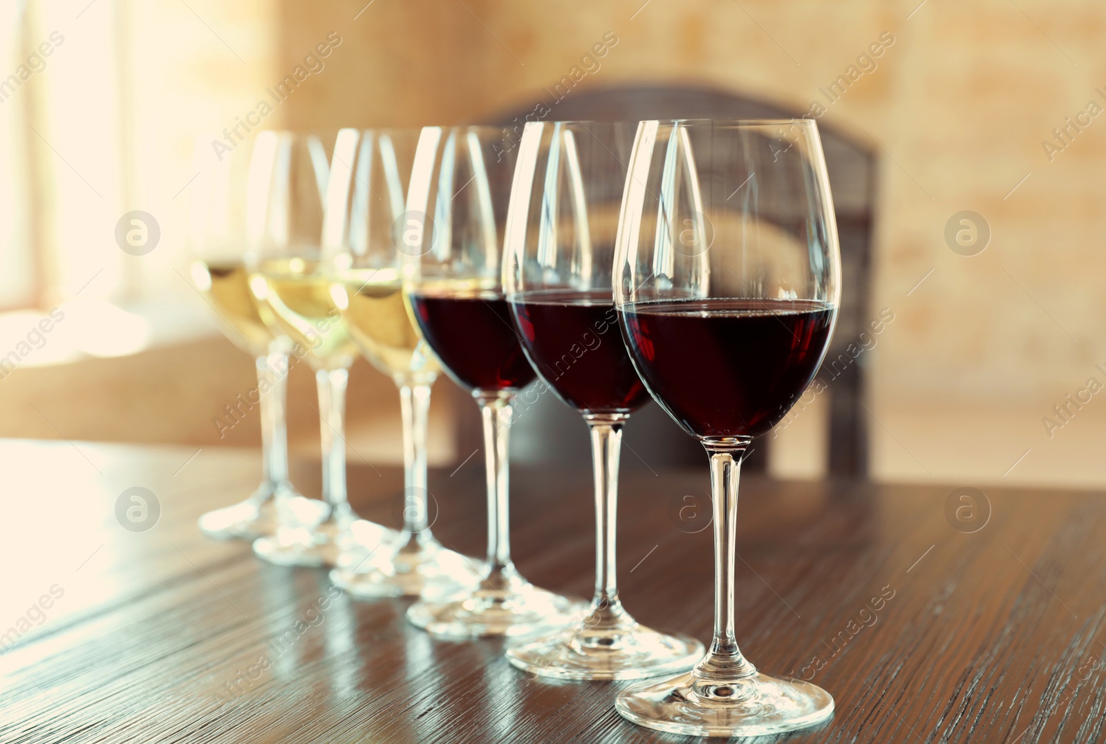 Photo of Glasses of white and red wines on wooden table