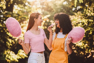 Image of Happy friends with cotton candies spending time together in park on sunny day