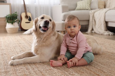 Cute little baby with adorable dog on floor at home