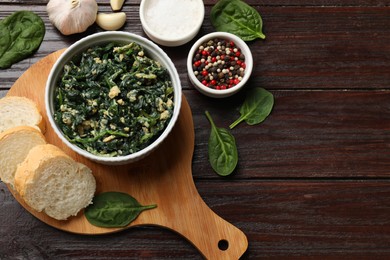 Photo of Tasty spinach dip with egg in bowl, spices and bread on wooden table, top view. Space for text