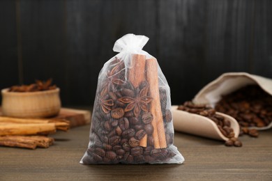Photo of Scented sachet with coffee beans, anise and cinnamon on wooden table, closeup