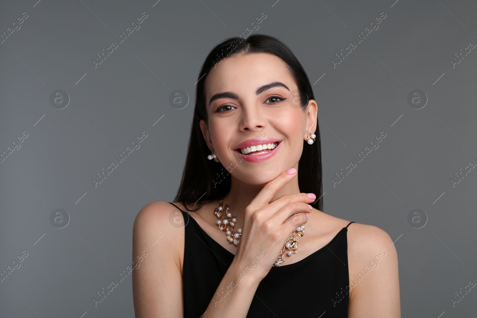 Photo of Beautiful young woman with elegant jewelry on dark grey background