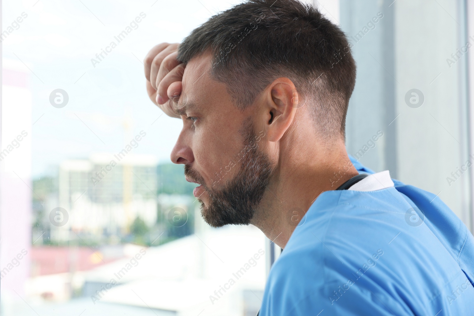 Photo of Exhausted doctor looking out of window in hospital