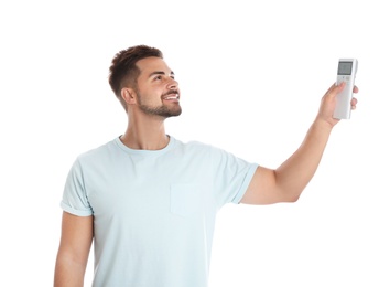 Photo of Happy young man operating air conditioner with remote control on white background