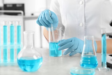 Photo of Scientist taking sample of light blue liquid in laboratory, closeup