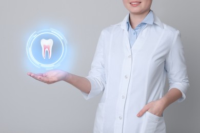 Dentist showing virtual model of tooth on light grey background, closeup