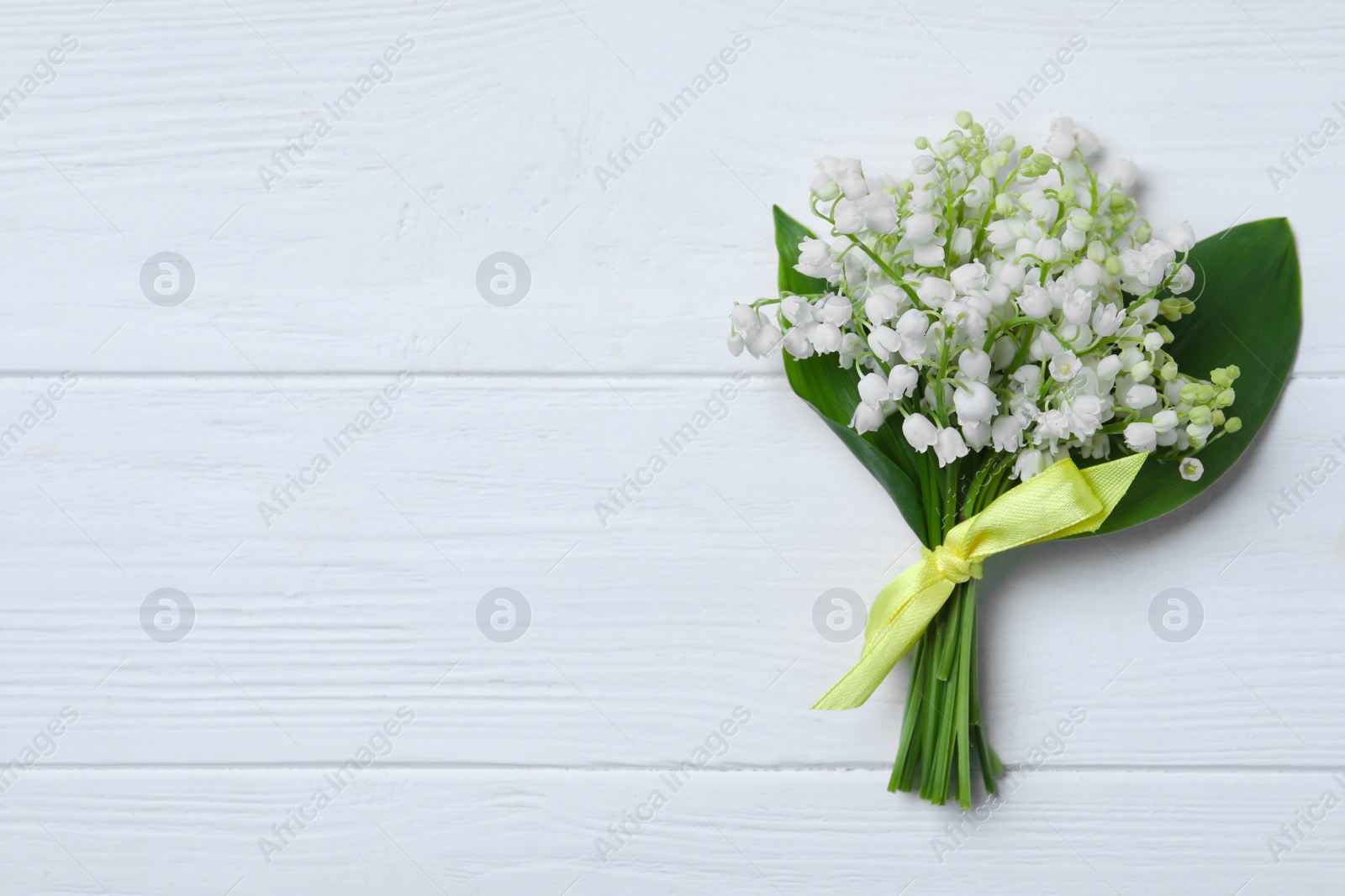 Photo of Beautiful lily of the valley flowers on white wooden table, top view. Space for text