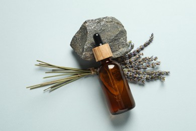 Photo of Flat lay composition with bottle of face serum, stone and beautiful flowers on light grey background
