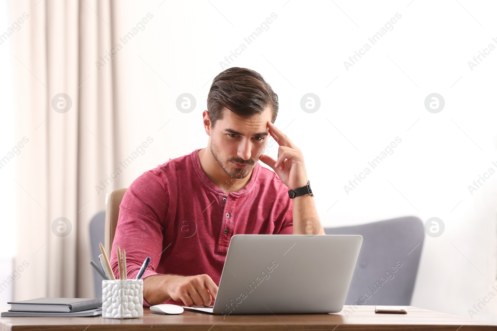 Photo of Handsome young man working with laptop at table in office