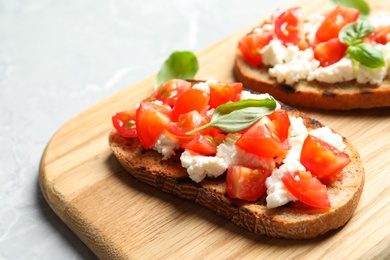 Board with tasty bruschettas on light table, closeup. Space for text