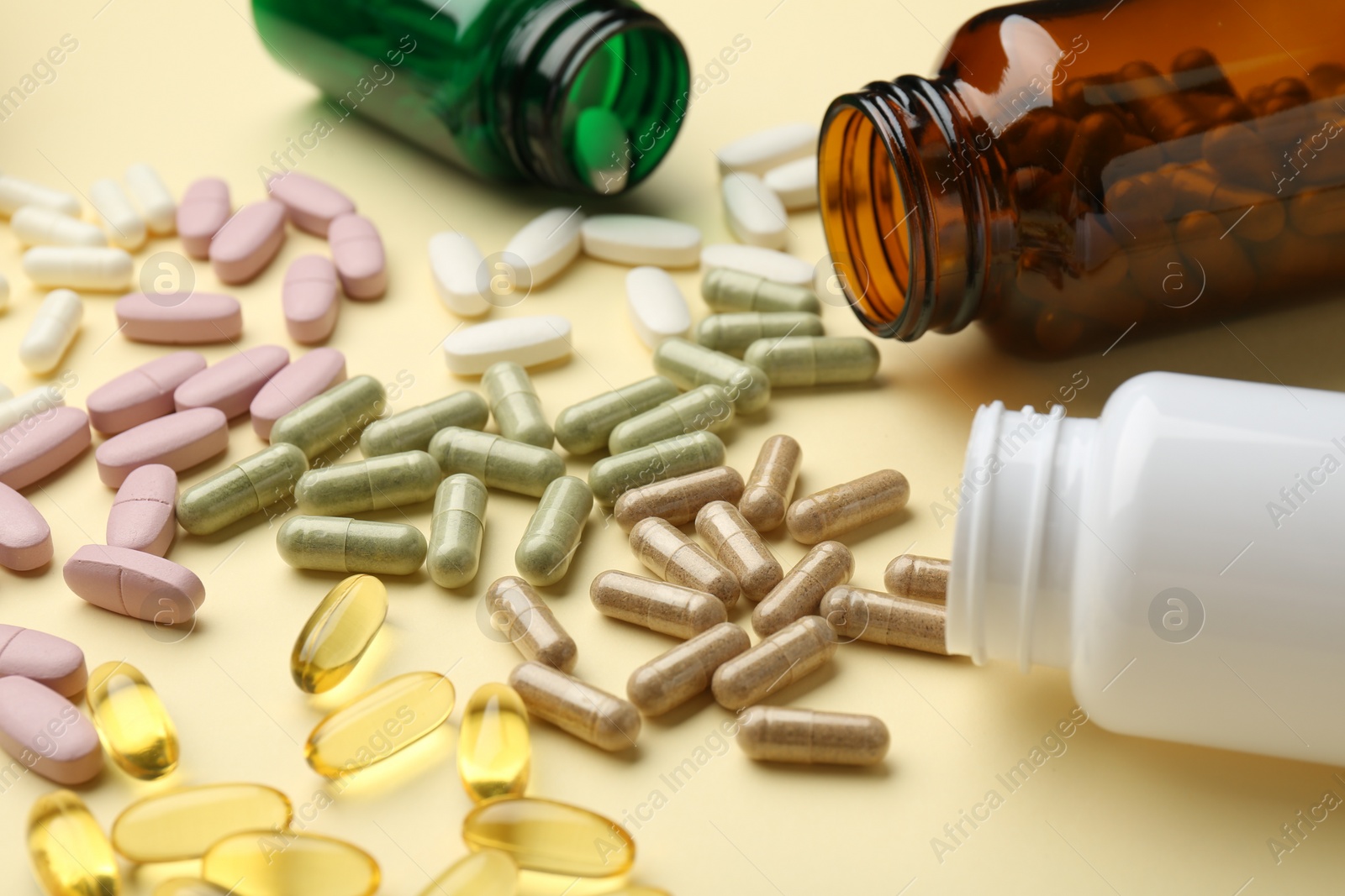 Photo of Many different vitamin pills and bottles on beige background, closeup