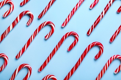 Photo of Sweet Christmas candy canes on light blue background, flat lay