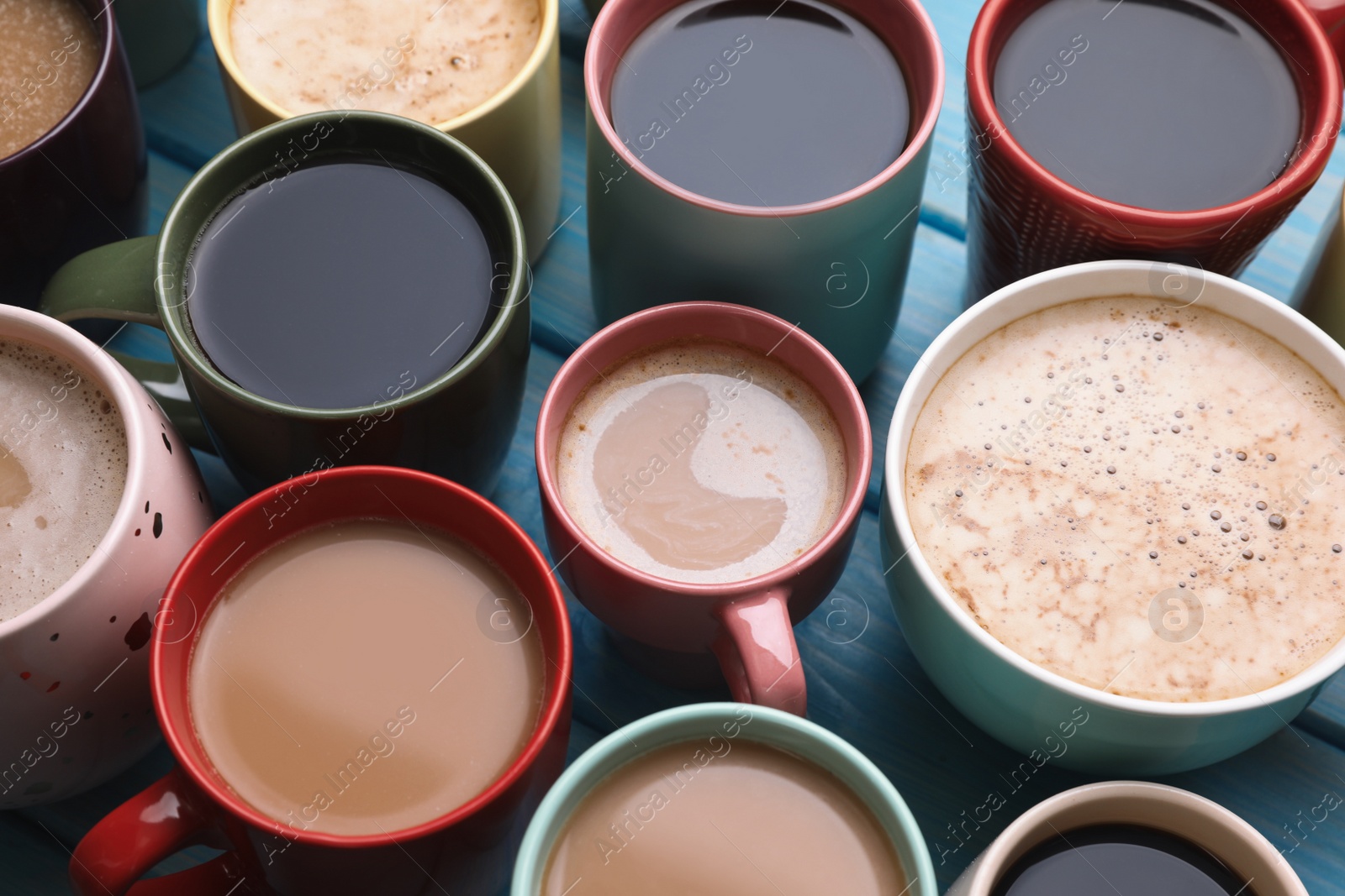 Photo of Many cups of different coffee drinks on light blue wooden table