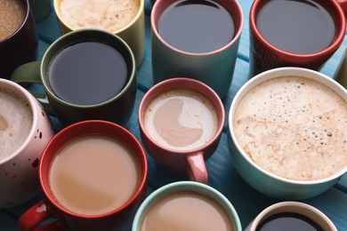 Many cups of different coffee drinks on light blue wooden table