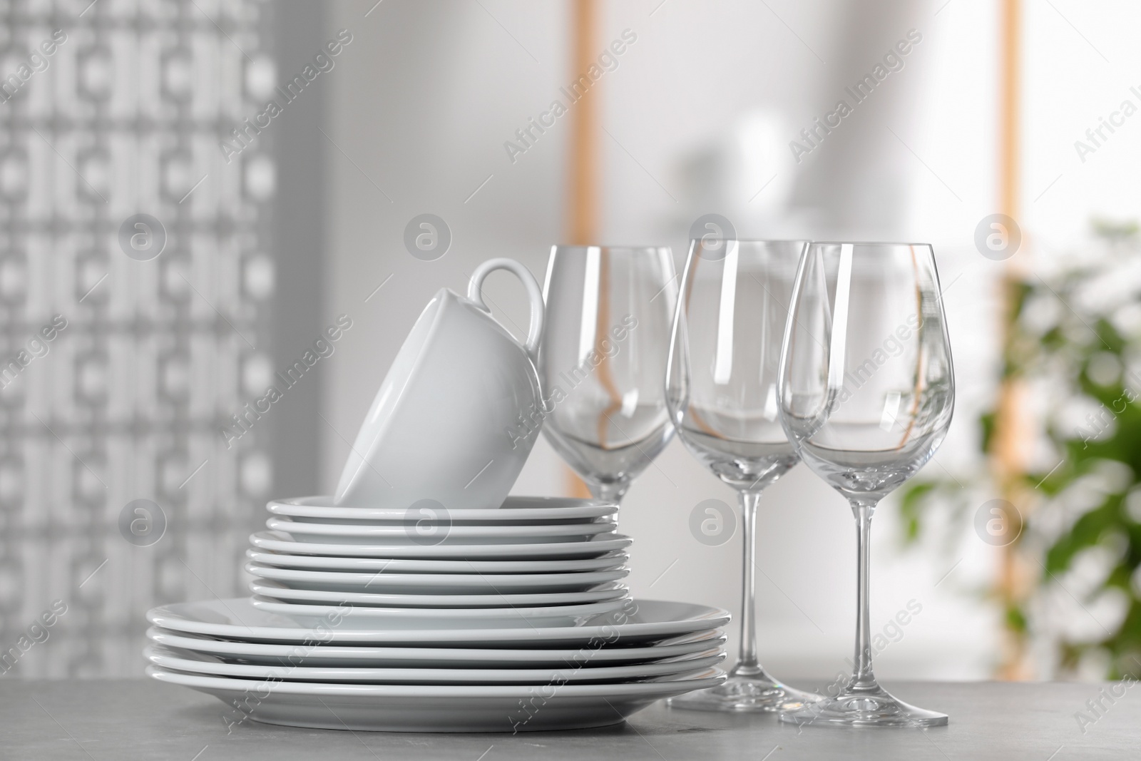 Photo of Set of clean dishware and glasses on light grey table