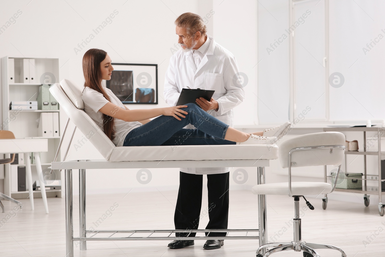 Photo of Orthopedist examining patient with injured knee in clinic