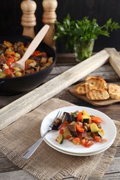 Photo of Delicious ratatouille served with bread on wooden table