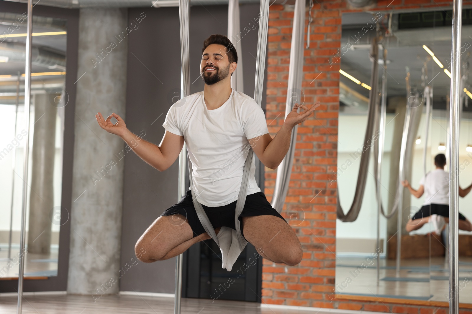 Photo of Young man practicing fly yoga on hammock in studio