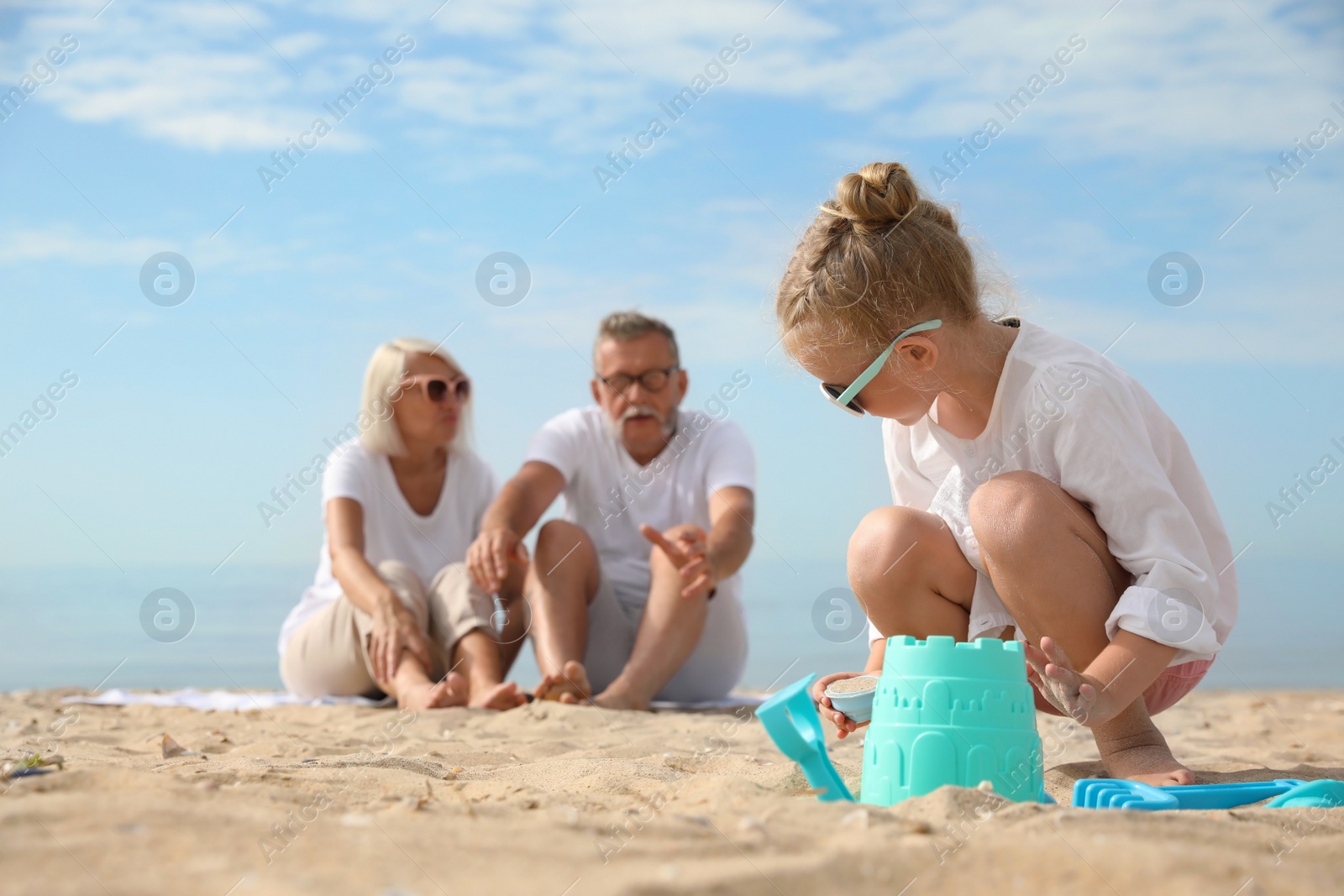 Photo of Little girl with grandparents on sea beach