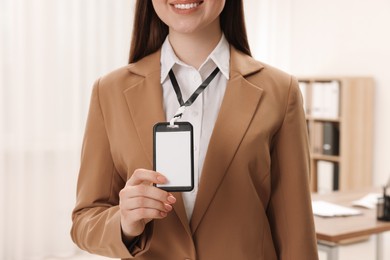 Woman with blank badge indoors, closeup view