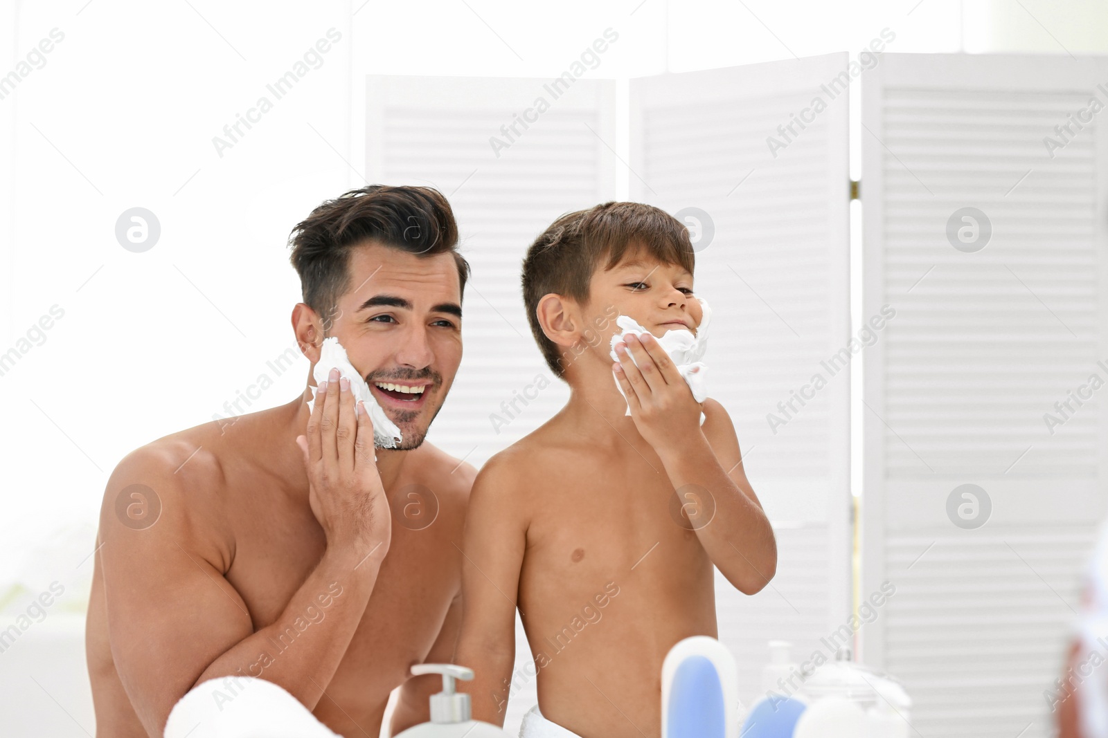 Photo of Father and son having fun while applying shaving foam in bathroom