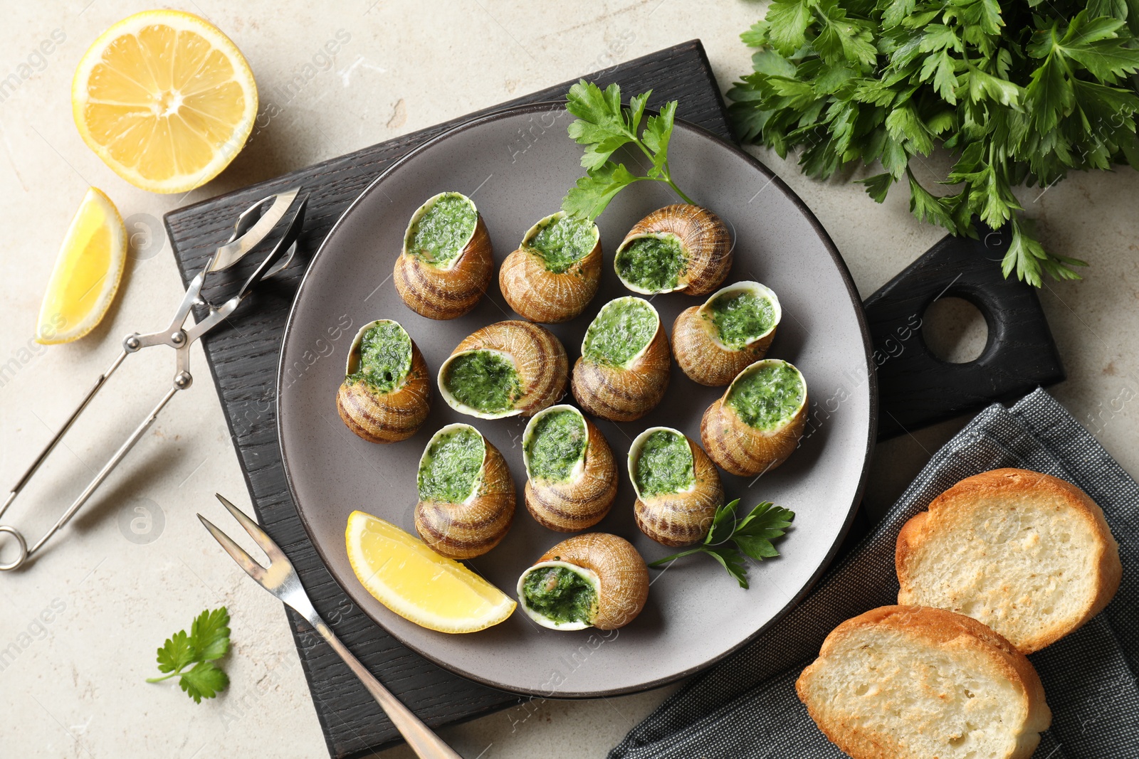 Photo of Delicious cooked snails served on light table, flat lay