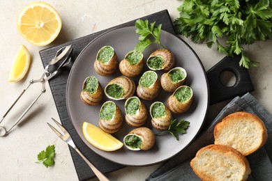 Photo of Delicious cooked snails served on light table, flat lay