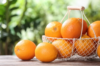 Photo of Basket and fresh oranges on wooden table. Space for text