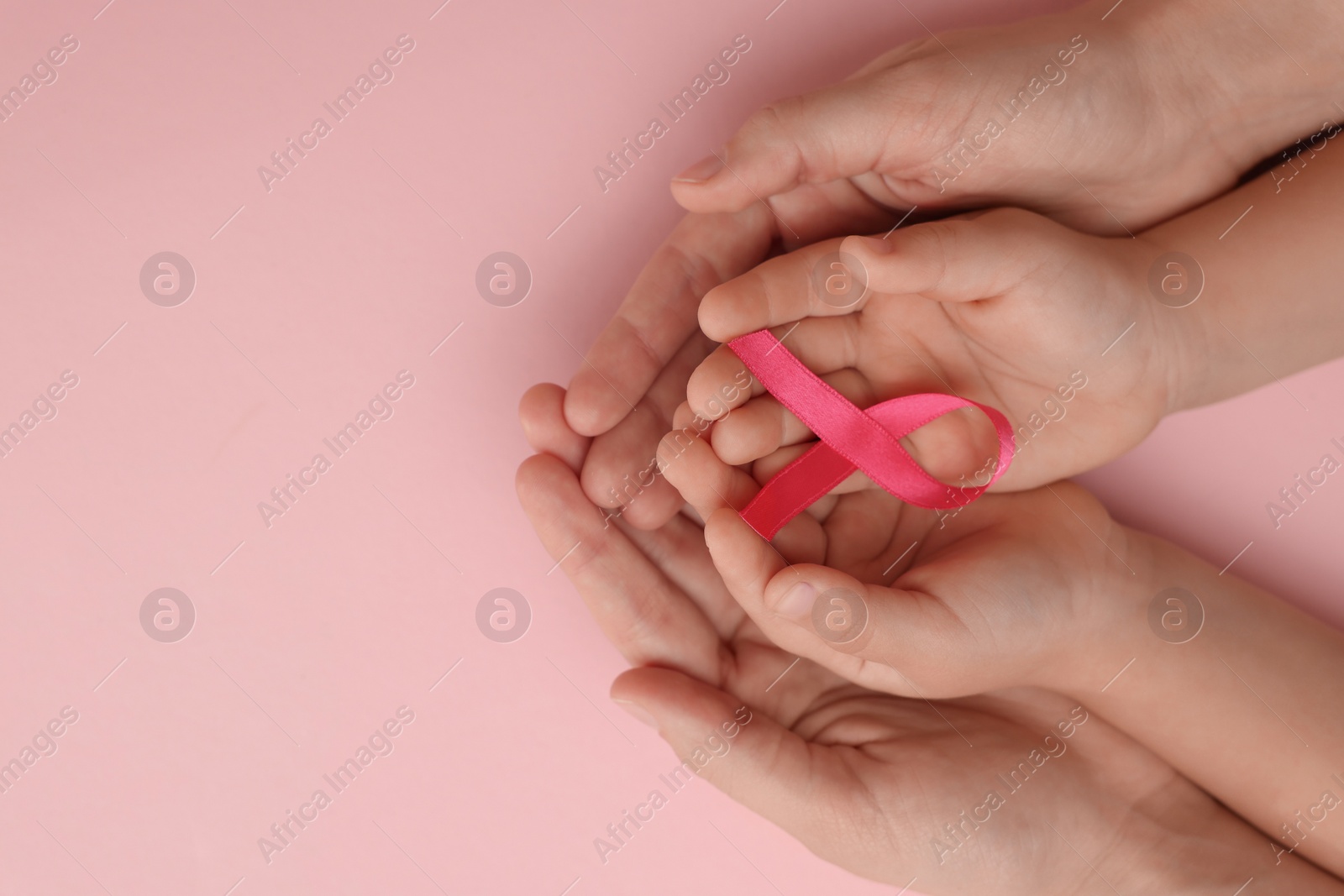 Photo of Woman and child holding pink ribbon on color background, top view with space for text. Breast cancer awareness