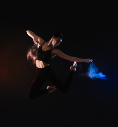 Photo of Professional acrobat with chalk powder exercising in dark studio