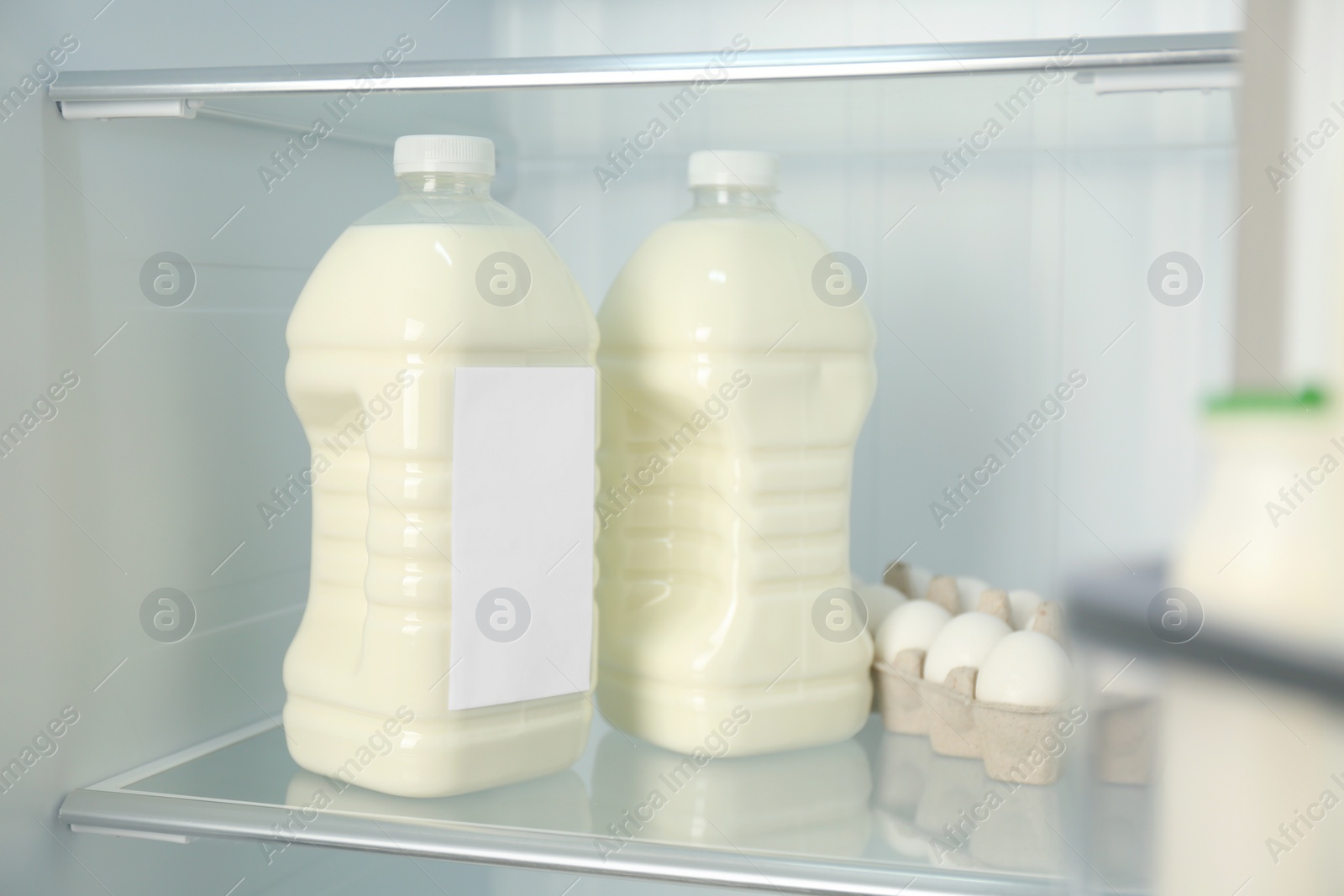 Photo of Gallons of milk near eggs in refrigerator, closeup