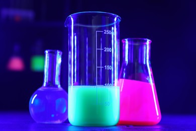 Laboratory glassware with luminous liquids on table