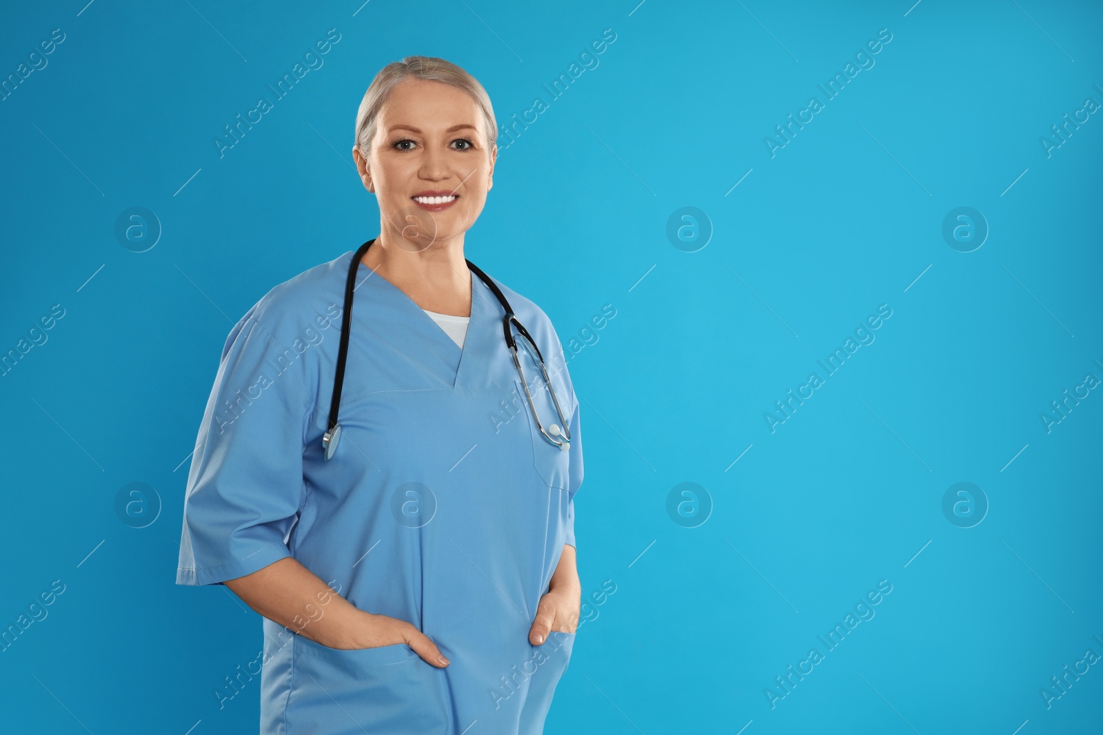 Photo of Portrait of mature doctor with stethoscope on blue background. Space for text