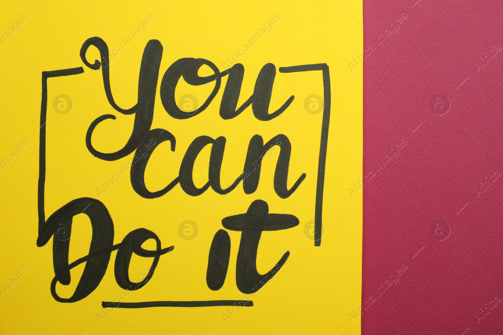 Photo of Yellow card with motivational phrase You Can Do It on burgundy background, closeup