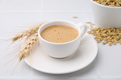 Photo of Cup of barley coffee, spikes and grains on white table, closeup