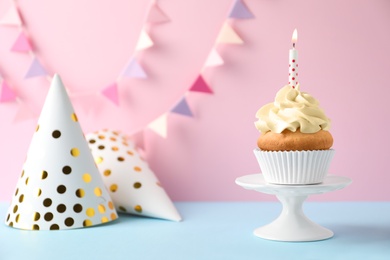 Dessert stand with delicious birthday cupcake on color background