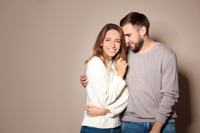 Image of Lovely couple in warm sweaters on beige background. Space for text