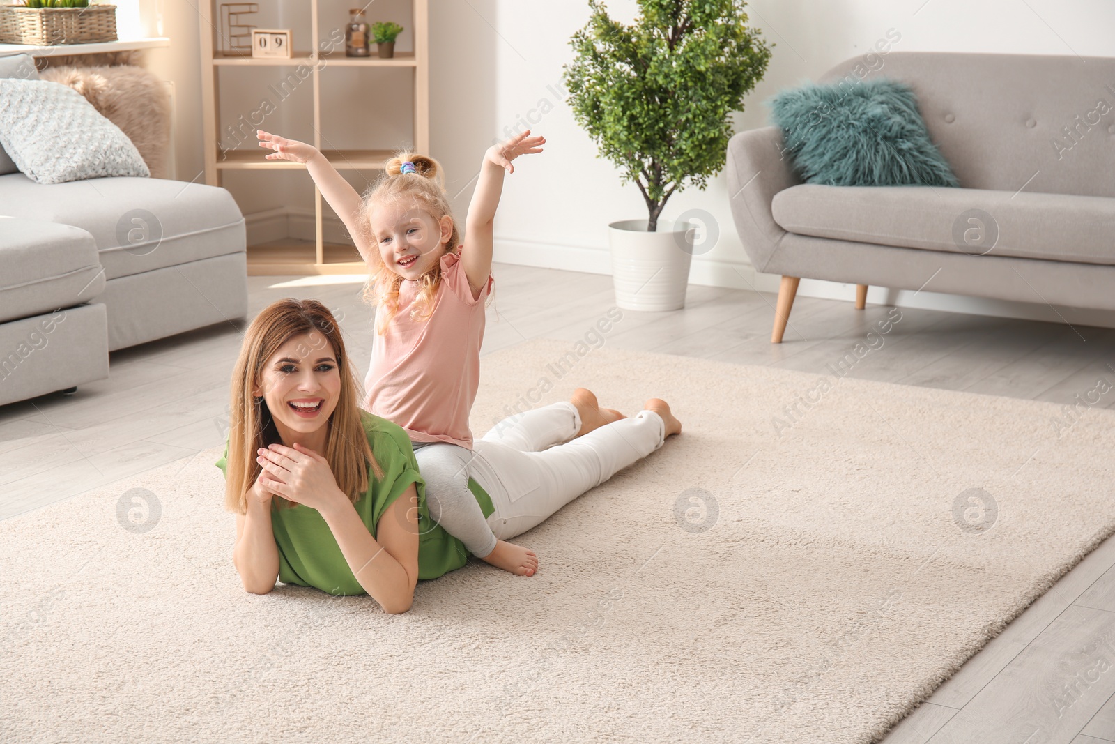 Photo of Cute little girl and her mother on cozy carpet at home