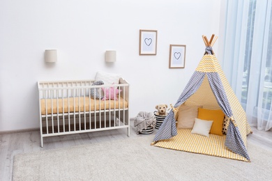 Photo of Cozy baby room interior with play tent and toys