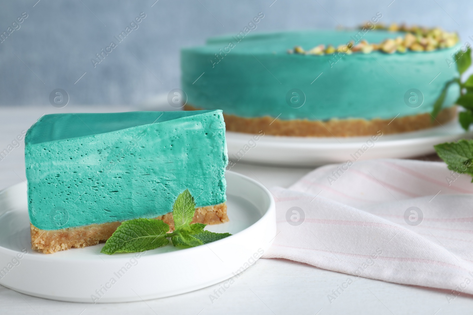 Photo of Delicious homemade spirulina cheesecake served on white wooden table