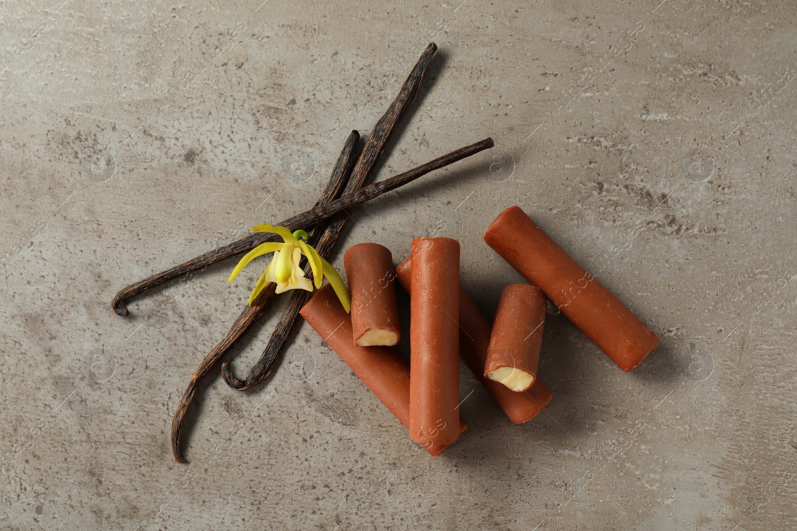 Photo of Glazed curd cheese bars, vanilla pods and flower on grey table, top view