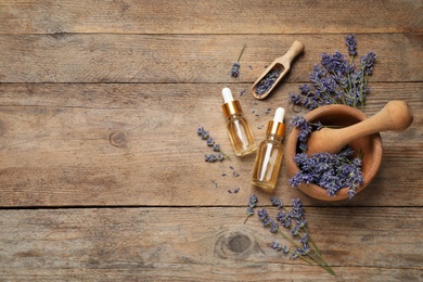 Photo of Flat lay composition with lavender flowers and natural essential oil on wooden table. Space for text