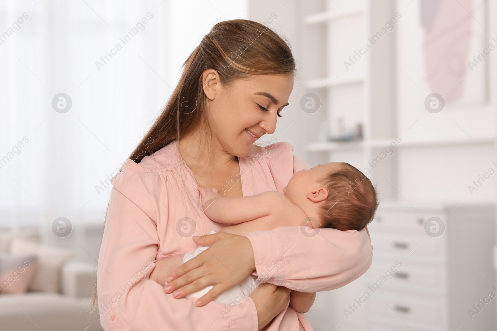 Photo of Mother holding her cute newborn baby in child's room