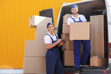 Photo of Male movers unloading boxes from van outdoors