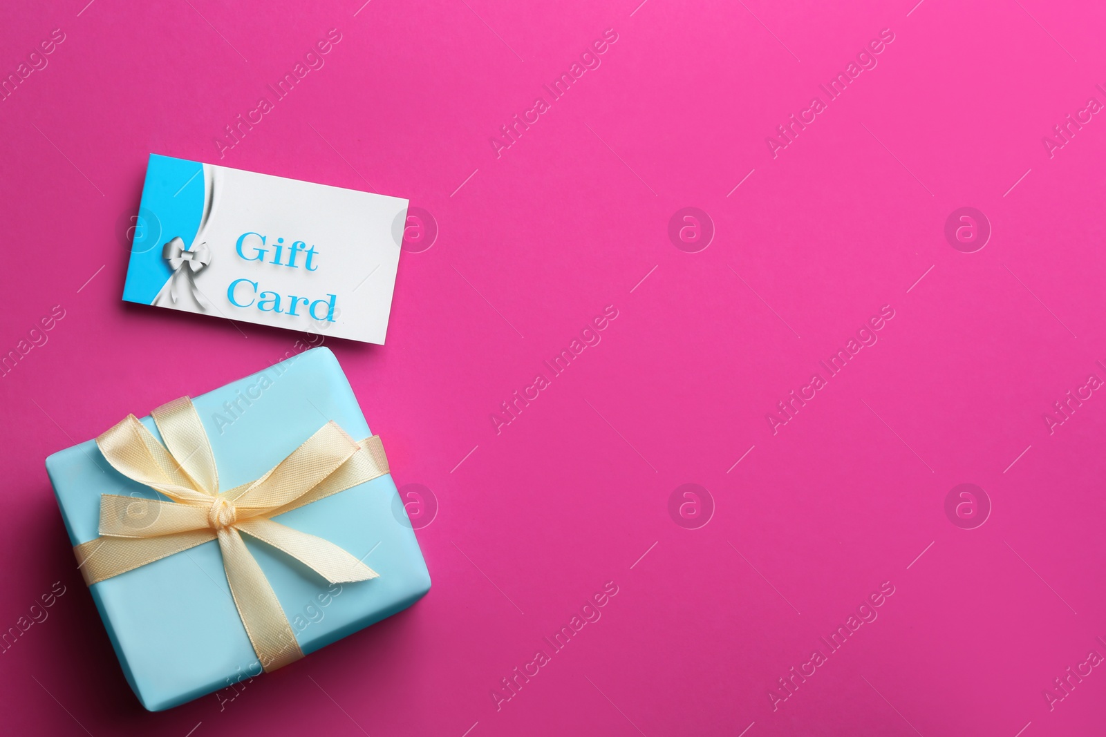 Photo of Gift card and present on pink background, flat lay. Space for text