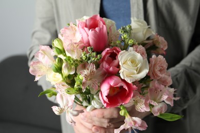 Photo of Man holding bouquet of beautiful flowers indoors, closeup