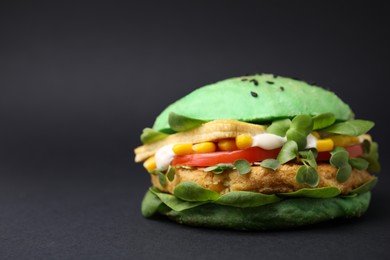 Tasty green vegan burger with vegetables, patty and microgreens on black background, closeup. Space for text